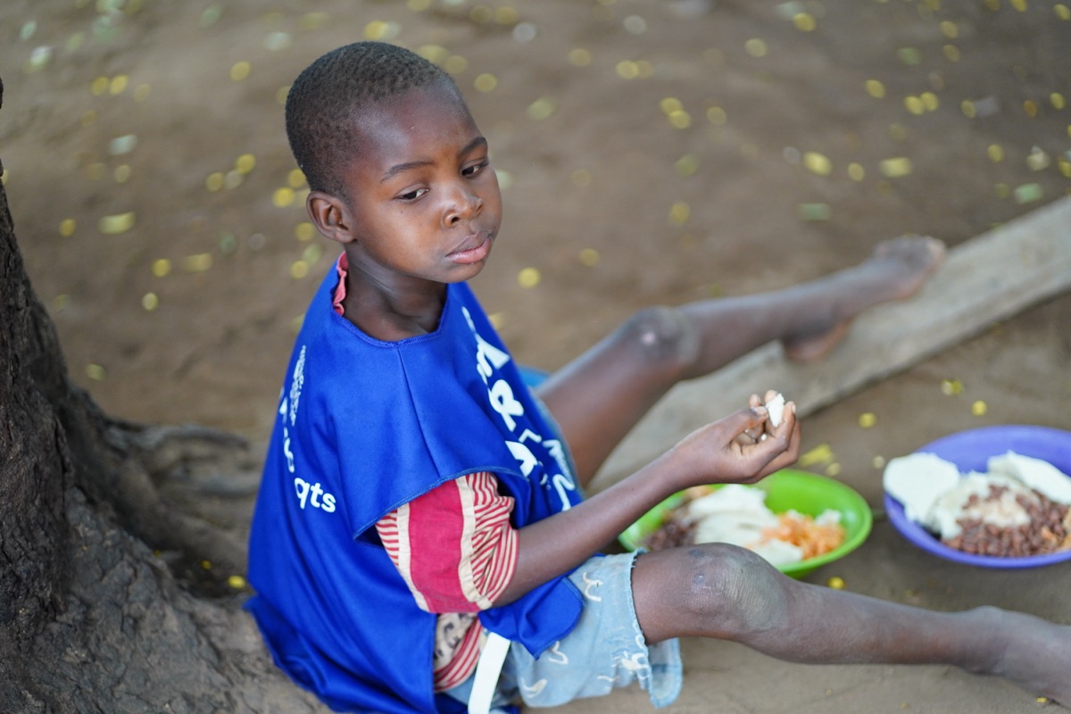 Boy eating his meal under a tree